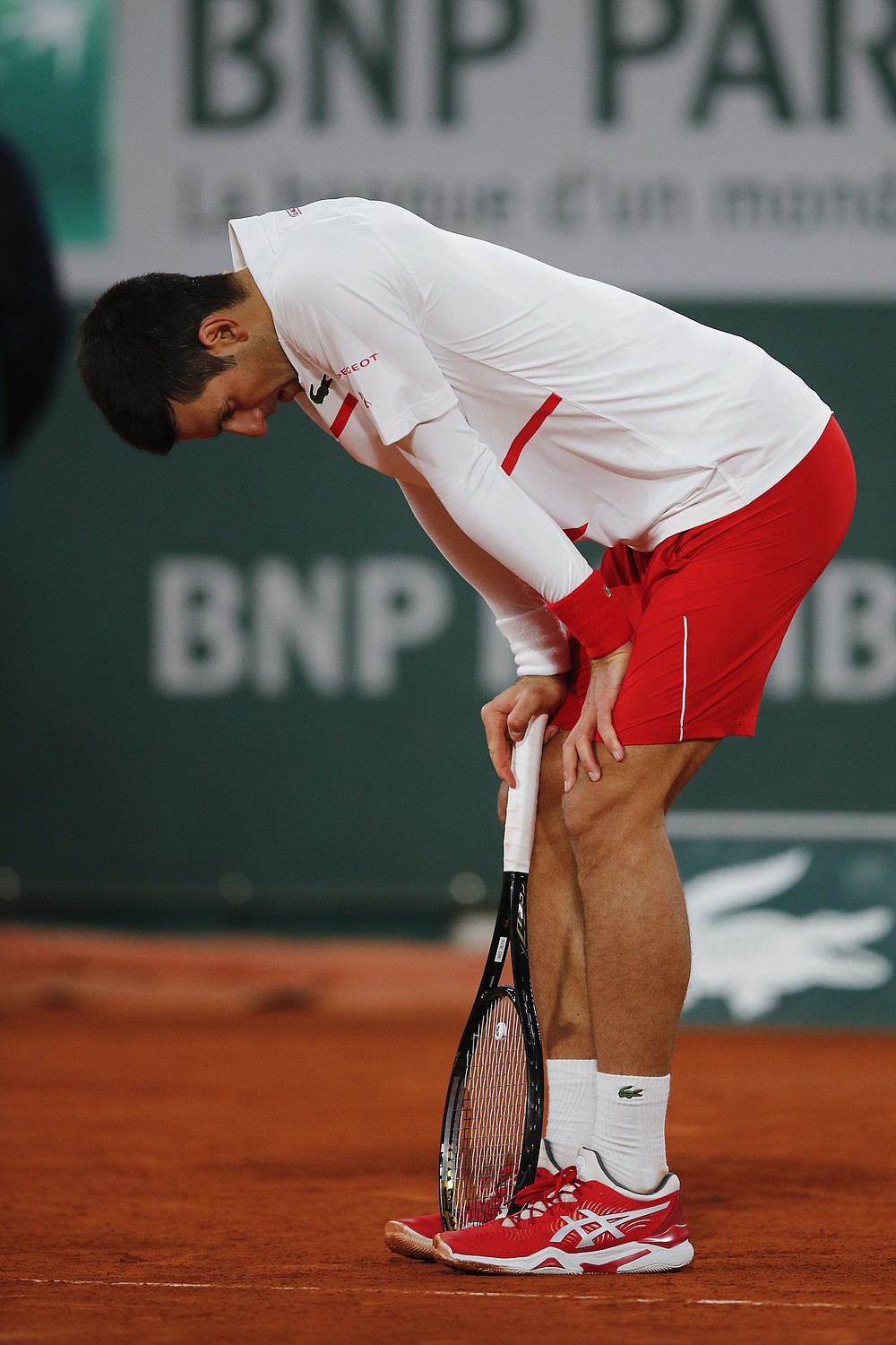 Serbia's Novak Djokovic leans on his racket in the quarterfinal match of the French Open tennis tournament against Spain's Pablo Carreno Busta at the Roland Garros stadium in Paris, France, Wednesday, Oct. 7, 2020. (AP Photo/Christophe Ena)