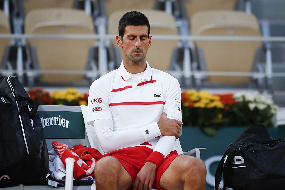 Serbia's Novak Djokovic massages his left upper arm in the quarterfinal match of the French Open tennis tournament against Spain's Pablo Carreno Busta at the Roland Garros stadium in Paris, France, Wednesday, Oct. 7, 2020. (AP Photo/Christophe Ena)