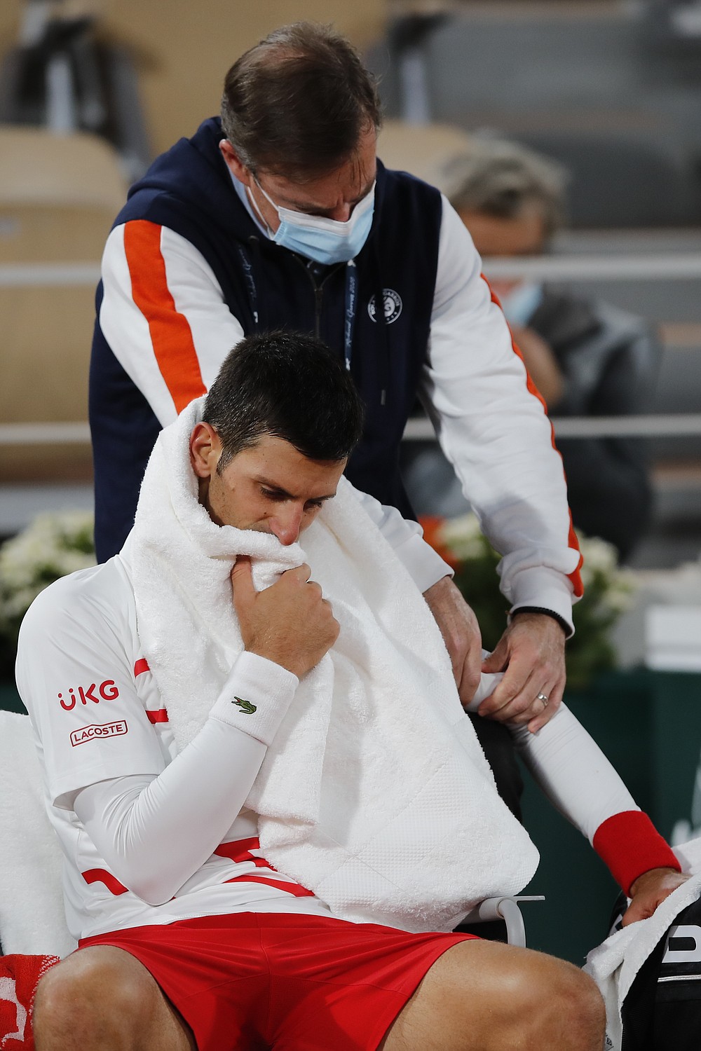 Serbia's Novak Djokovic receives medical assistance for a left arm injury in the quarterfinal match of the French Open tennis tournament against Spain's Pablo Carreno Busta at the Roland Garros stadium in Paris, France, Wednesday, Oct. 7, 2020. (AP Photo/Christophe Ena)