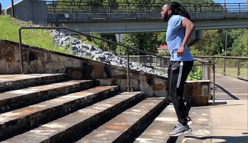 Emmanuel Eyiuche does the Staircase Squat Jump on wide stone steps next to Two Rivers Bridge in Little Rock. (Arkansas Democrat-Gazette/Celia Storey)