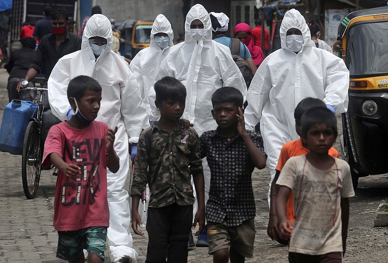 FILE - In this Friday, July 10, 2020 file photo, health workers wearing protective clothing arrive to screen people for COVID-19 symptoms at a slum in Mumbai, India. Up to 150 million people could slip into extreme poverty, living on less than $1.90 a day, by late next year depending on how badly economies shrink during the COVID-19 pandemic, the World Bank said Wednesday, Oct. 7, 2020 in an outlook grimmer than before. (AP Photo/Rafiq Maqbool, File)