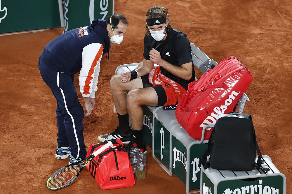 Greece's Stefanos Tsitsipas receives medical assistance in the semifinal match of the French Open tennis tournament against Serbia's Novak Djokovic at the Roland Garros stadium in Paris, France, Friday, Oct. 9, 2020. (AP Photo/Alessandra Tarantino)
