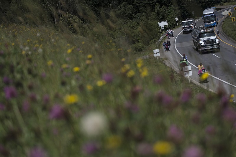 A group of Venezuelan migrants walk towards Bogota, in Tunja, Colombia, Tuesday, Oct. 6, 2020. South American roads have become harder to negotiate for poor migrants with no money for bus tickets, shelters remain closed due to the COVID-19 pandemic and locals who fear contagion are less likely to help out with rides and food. (AP Photo/Ivan Valencia)