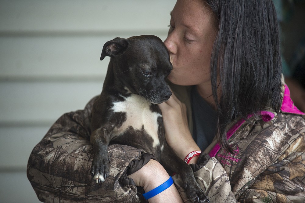 Savannah LeFleur kisses, Deuce, a dog she found wandering during Hurricane Laura several weeks ago in Bell City, La., Friday, Oct. 9, 2020. The two huddle in her car port as rain from Hurricane Delta moves into the state. Residents in south Louisiana braced to relive a nightmare Friday as bands of rain from approaching Hurricane Delta began soaking the same area of the state that was badly battered by a deadly hurricane six weeks ago. (Chris Granger/The Advocate via AP)