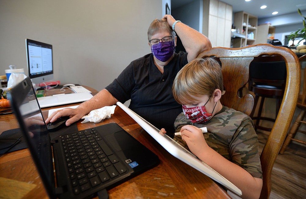 Second-grader Corwin McNair, 7, works on mathematics problems Thursday, Oct. 8, 2020, with the help of his grandmother and retired school teacher, Mary Tannehill, at the family's home south of Elkins. School districts are working to maintain connection to students as instruction in some areas moves to a fully online model because of the current coronavirus pandemic. Visit nwaonline.com/201011Daily/ for today's photo gallery.
(NWA Democrat-Gazette/Andy Shupe)