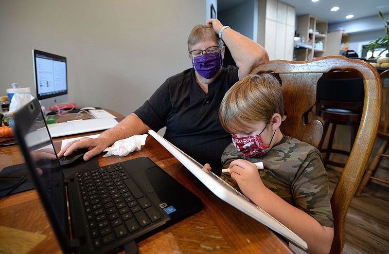 Second-grader Corwin McNair, 7, works on mathematics problems Thursday, Oct. 8, 2020, with the help of his grandmother and retired school teacher, Mary Tannehill, at the family's home south of Elkins. School districts are working to maintain connection to students as instruction in some areas moves to a fully online model because of the current coronavirus pandemic. Visit nwaonline.com/201011Daily/ for today's photo gallery. 
(NWA Democrat-Gazette/Andy Shupe)