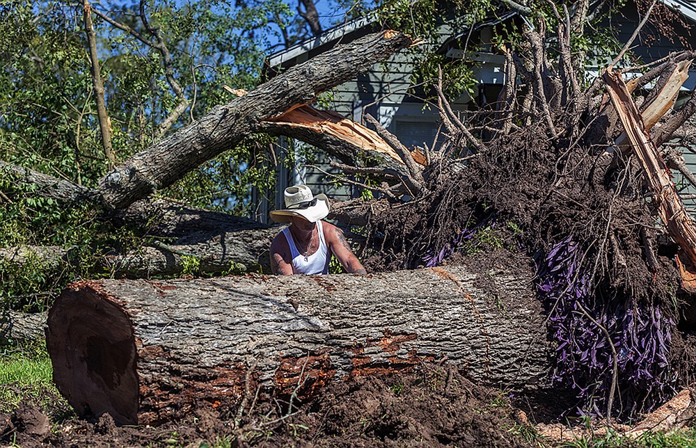 Michael McDonald clears trees after Hurricane Delta passed the area in Jennings, La., Saturday, Oct. 10, 2020. The day after Hurricane Delta blew through besieged southern Louisiana, residents started the routine again: dodging overturned cars on the roads, trudging through knee-deep water to flooded homes with ruined floors and no power, and pledging to rebuild after the storm. (Scott Clause /The Daily Advertiser via AP)