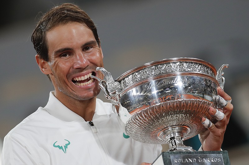 Spain's Rafael Nadal bites the trophy as he celebrates winning the final match of the French Open tennis tournament against Serbia's Novak Djokovic in three sets, 6-0, 6-2, 7-5, at the Roland Garros stadium in Paris, France, Sunday, Oct. 11, 2020. (AP Photo/Michel Euler)