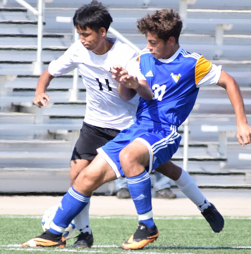 RICK PECK/SPECIAL TO MCDONALD COUNTY PRESS McDonald County's Saw Eh (11) battles Frantisek Pavlovsky of Parsons for control of the ball during the Mustangs' 4-1 win on Oct. 10 at the Joplin Eagles Soccer Tournament.