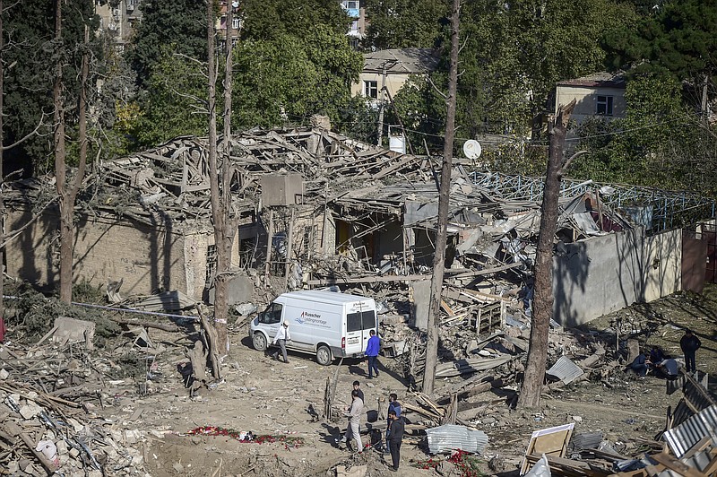 People look at the destroyed houses a day after shelling by Armenian's artillery during fighting over the separatist region of Nagorno-Karabakh, in Ganja, Azerbaijan, Monday, Oct. 12, 2020. Armenia and Azerbaijan on Monday have accused each other of attacks over the separatist territory of Nagorno-Karabakh despite a cease-fire deal brokered by Russia in an effort to end the worst outbreak of hostilities in decades. (AP Photo)