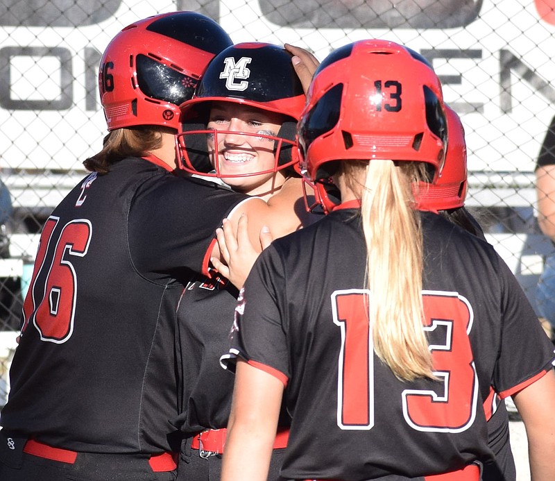 RICK PECK/SPECIAL TO MCDONALD COUNTY PRESS McDonald County's Neveah Dodson gets a hug from teammate Madeline McCall after hitting a grand slam to lead the Lady Mustangs to a 15-1 win over Springfield Hillcrest on Oct. 12 at MCHS.