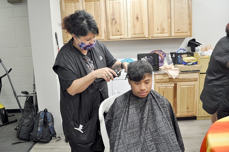 RACHEL DICKERSON/MCDONALD COUNTY PRESS Tanya Stone, left, of Shag-a-delx Salon gives a haircut to McDonald County High School senior Castro Samson. Stone and another employee donated haircuts to students of the English language learners class at the high school.