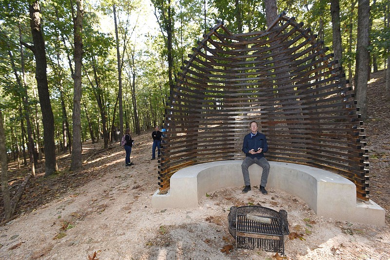 Brad Kingsley sits beside the campfire ring on Oct. 2 2020 at one of six bikepacking campsites that will open soon at Hobbs State Park-Conservation Area. The sites are along the Karst Loop mountaina biking and hiking trail near Beaver Lake. Metal sculpture is part of each site, as well as in a new parking area being built near the Hobbs visitor center.
(NWA Democrat-Gazette/Flip Putthoff)