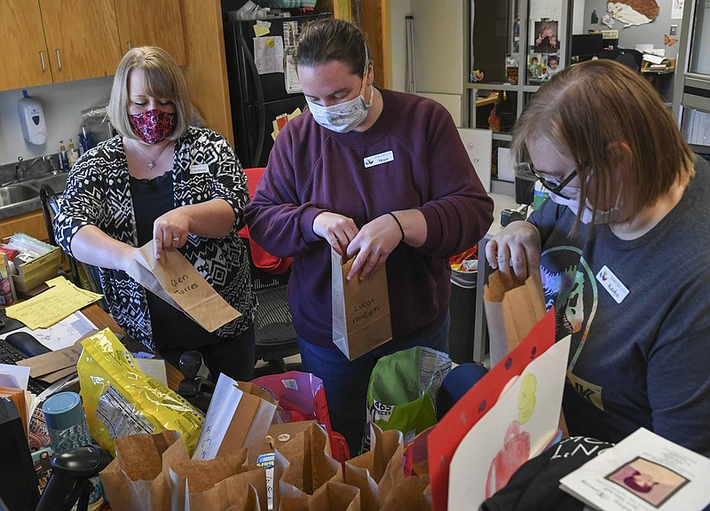 Young adult librarian Brittany Chavez, left, helps Megan James and Katelyn Holmes put together candy bags for a library outreach program at the Garland County Library on Wednesday. - Photo by Grace Brown of The Sentinel-Record