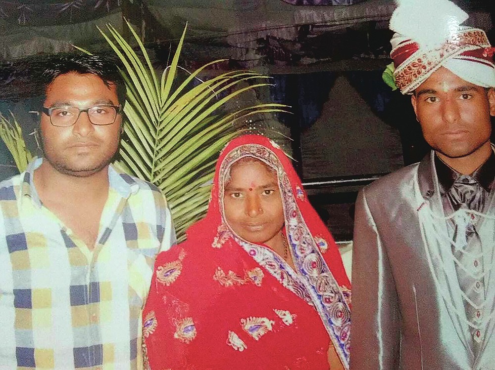 In this Feb. 3, 2014, photo, Joginder Chaudhary, left, and Kapil pose for a picture with their mother Premlata on Kapil's wedding day, in Jhantala, Madhya Pradesh, India. After the virus killed the 27-year-old Chaudhary in late July 2020, his mother wept inconsolably. With her son gone, Premlata Chaudhary said, how could she go on living? Three weeks later, on Aug. 18, the virus took her life, too — yet another number in an unrelenting march toward a woeful milestone. (Courtesy of Kapil Chaudhary via AP)