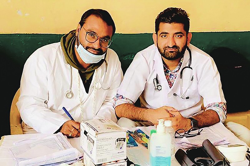 In this October 2019 photo provided by Bharat Sangwan, Joginder Chaudhary, left, and his friend and colleague Sangwan volunteer at a medical camp for women. After the virus killed the 27-year-old Chaudhary in late July 2020, his mother wept inconsolably. With her son gone, Premlata Chaudhary said, how could she go on living? Three weeks later, on Aug. 18, the virus took her life, too — yet another number in an unrelenting march toward a woeful milestone. (Courtesy of Bharat Sangwan via AP)