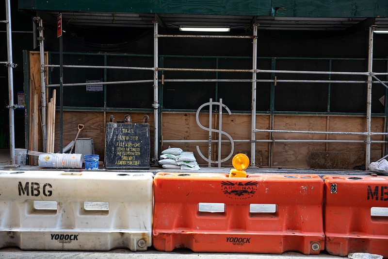 A dollar sign bike rack, designed by David Byrne, stands surrounded by scaffolding and construction material along Wall Street in New York on July 20, 2020. MUST CREDIT: Bloomberg photo by Michael Nagle. story.lead_photo.caption