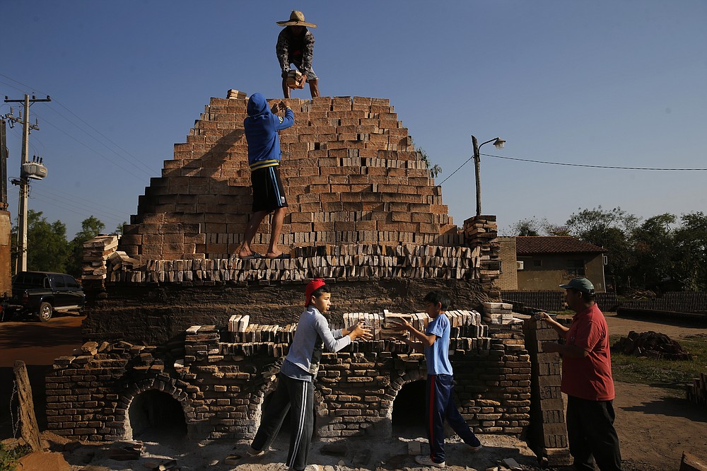 Children work with their relatives to load a kiln with clay bricks in Tobati, Paraguay, Friday, Sept. 4, 2020. In many of the small Tobati brick factories, locals begin to work at an early age to complement their family's income. (AP Photo/Jorge Saenz)