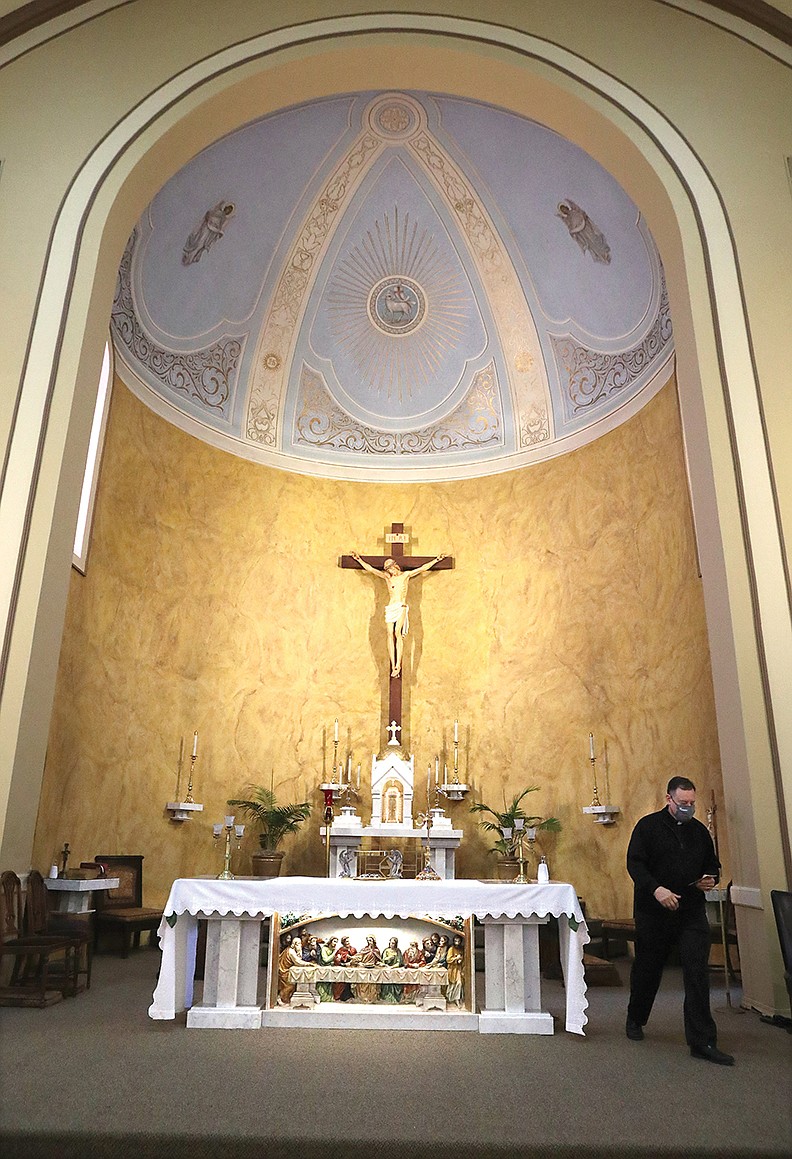 The Rev. George Sanders walks near the altar of the Catholic Church of St. John the Baptist on Friday. - Photo by Richard Rasmsusen of The Sentinel-Record