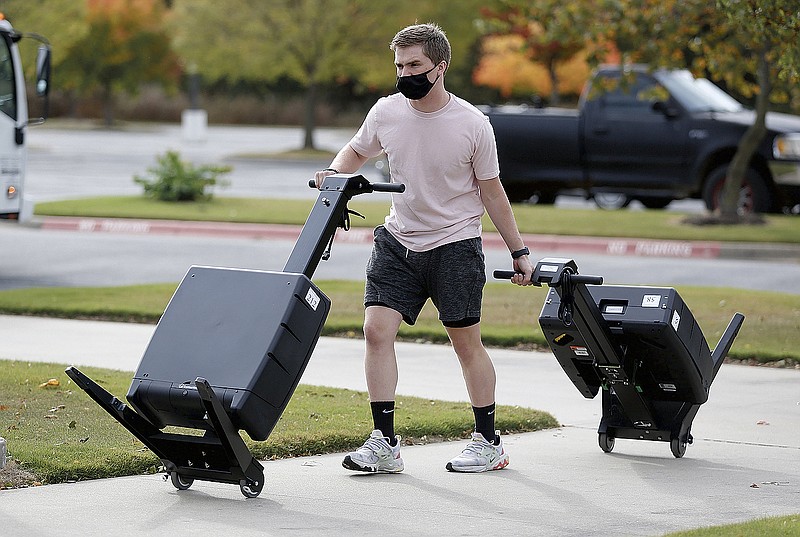 Tristin McCammon, with the Washington County Election Commission, moves voting machines with other staff members Thursday, October 15, 2020, to set up a voting center inside the visitors locker room at Arrest Ballpark in Springdale. Early voting for the November 3rd general election begins Monday. Check out nwaonline.com/201018Daily/ and nwadg.com/photos for a photo gallery.(NWA Democrat-Gazette/David Gottschalk)