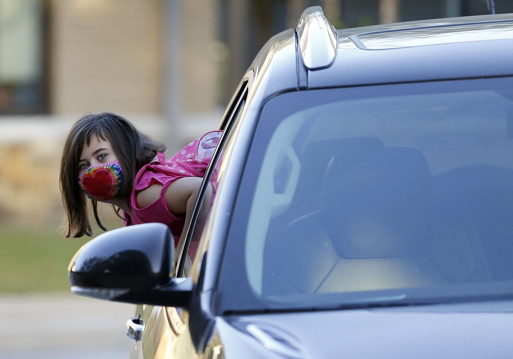 Liberty Strickland, a second grade student at The New School, leans out of the car Thursday, October 1, 2020, before she is dropped off at the school for a day of classes in Fayetteville. Check out nwadg.com/photos for a photo gallery.(NWA Democrat-Gazette/David Gottschalk)