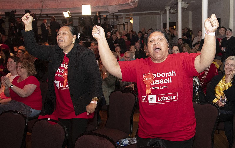 New Zealand Labour Party supporters react as results are showed on a screen at a party event after the polls closed in Auckland, New Zealand, Saturday, Oct. 17, 2020. (AP Photo/Mark Baker)