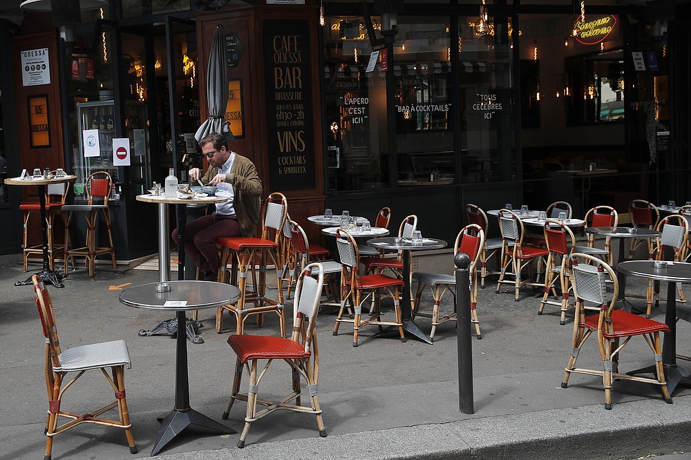 FILE - In this Monday, June 15, 2020 file photo, a man takes his lunch on a terrace at a restaurant, in Paris. Europe’s economy was just catching its breath from what had been the sharpest recession in modern history. A resurgence in coronavirus cases this month, Oct. 2020, risks undoing that and will likely turn what was meant to be a period of healing for the economy into a lean winter of job losses and bankruptcies. (AP Photo/Francois Mori, File)