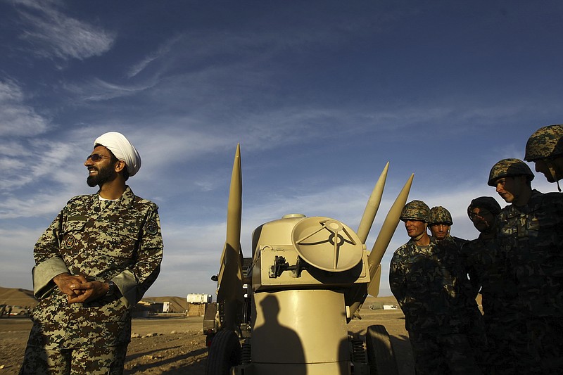 FILE - In this Nov. 13, 2012 file photo, an Iranian clergyman stands next to missiles and army troops, during a manoeuvre, in an undisclosed location in Iran. A decade-long U.N. arms embargo on Iran that bared it from purchasing foreign weapons like tanks and fighter jets expired Sunday, Oct. 18, 20202, as planned under its nuclear deal with world powers, despite objections from the United States. (Majid Asgaripour/Mehr News Agency via AP, File)