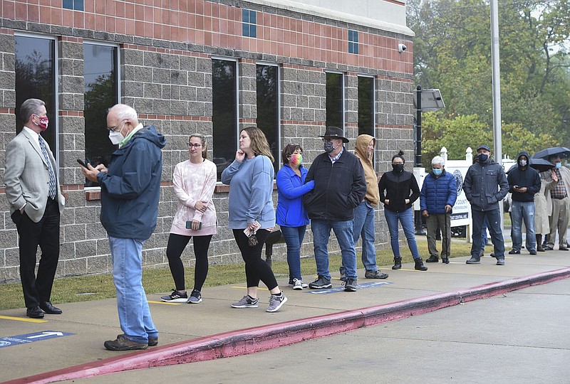 Voters stand in line under a light mist Monday at the Benton County Administration building in Bentonville. Early voting started Monday. The expanded and renovated Quorum Courtroom is being used as a early voting site. Go to nwaonline.com/201020Daily/ for today's photo gallery. 

(NWA Democrat-Gazette/Charlie Kaijo)