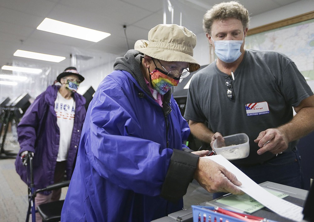 Benton County Election Commission member Thomas Bridges (right) helps Mary Thomas (left) submit her ballot Monday at the county administration building in Bentonville.
(NWA Democrat-Gazette/Charlie Kaijo)