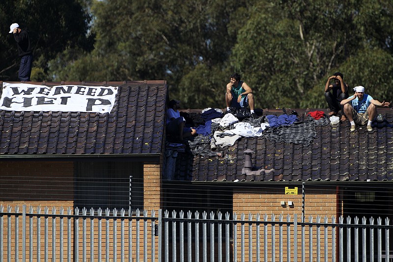 FILE - In this April 12, 2011, file photo, Five male detainees gather on a rooftop of the Villawood Detention Center in Sydney, Australia. The United States is expected to have resettled more than 1,100 refugees by early next year under a deal President Donald Trump reluctantly honored with Australia, an Australian official said on Monday, Oct. 19, 2020. (AP Photo/Rick Rycroft, File)