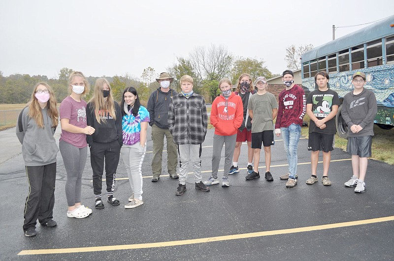 RACHEL DICKERSON/MCDONALD COUNTY PRESS Teacher Keith Jones and the eighth grade McDonald County SOPE class are pictured at central office next to the art bus on Tuesday. They were working on a project mapping the trails behind central office.