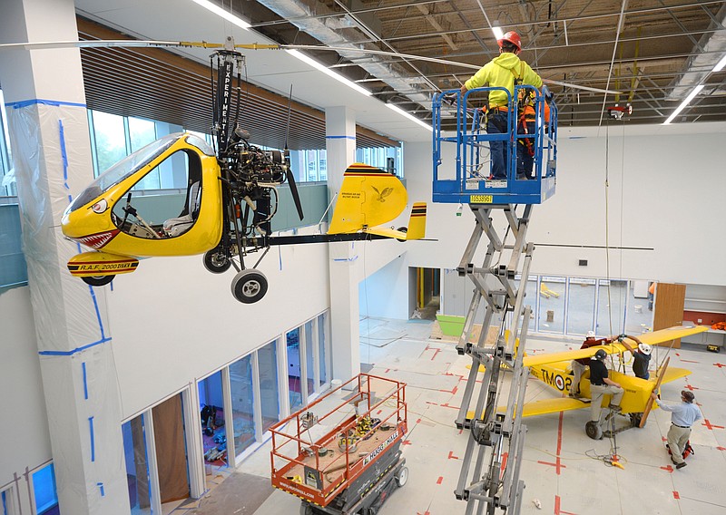 A gyrocopter hangs Tuesday from the ceiling in the preschool area of the Fayetteville Public Library's expansion as personnel from the library and Crossland Construction work out the details of lifting a De Havilland DH.82 Tiger Moth to the ceiling. The aircraft are from the Arkansas Air and Military Museum and will be joined by a third plane painted red that will be delivered in the coming days in pieces and reassembled inside before it too will be suspended from the ceiling.
(NWA Democrat-Gazette/Andy Shupe)