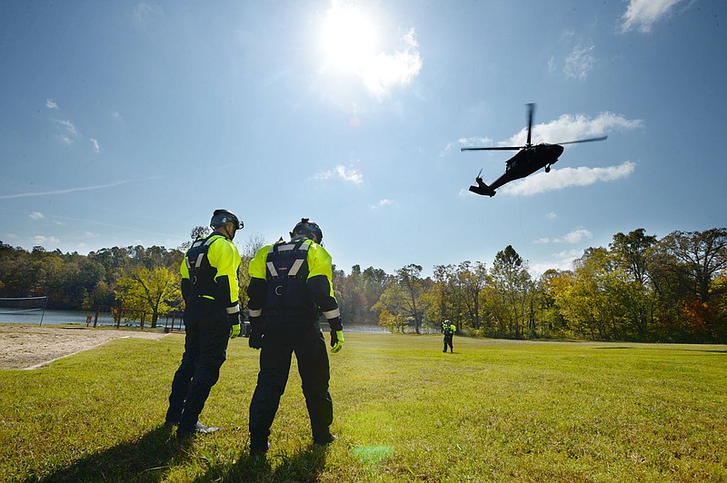 Northwest Arkansas Task Force 1 members watch Wednesday, Oct. 21, 2020, as team members are lowered to the ground from a Sikorsky UH-60 Black Hawk helicopter during training at Lake Wedington. The Arkansas National Guardâ€šÃ„Ã´s 77th Theater Aviation Brigade conducted routine helicopter rescue training with Northwest Arkansas Task Force 1 members as part of the Arkansas Helicopter Rescue Team training at Lake Wedington near Fayetteville. The training acquaints local rescue personnel with military aircraft, rescue equipment and communications to prepare for a joint rescue or recovery. Visit nwaonline.com/201022Daily/ for today's photo gallery. 
(NWA Democrat-Gazette/Andy Shupe)