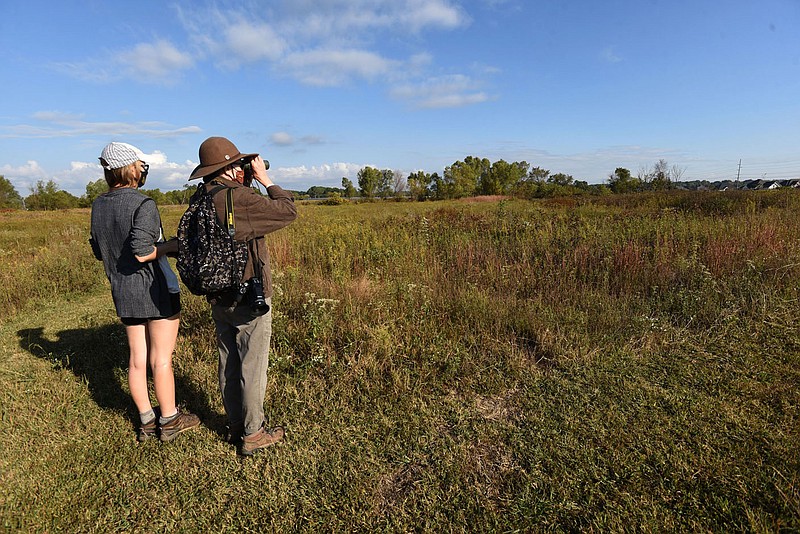 Samantha Heller and Joan Reynolds take in the view of native grasses, plants and wildflowers on Oct. 9 2020 at Woolsey Wet Prairie on the west edge of Fayetteville. Mowed trails allow easy walking access through the tract. Much of the prairie is a wetland after sufficient rainfall, especially in the spring.
(NWA Democrat-Gazette/Flip Putthoff)