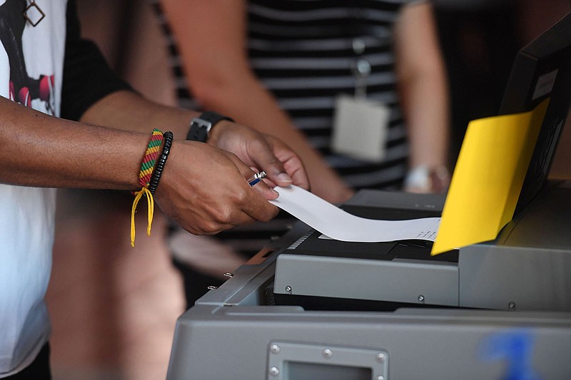 Kelvin Summerville drops his ballot in a ballot box while voting Thursday at Bud Walton Arena in Fayetteville. The arena will only be open for voting Friday and Saturday. The Washington County Election Commission approved the short term voting center because of covid-19. Visit nwaonline.com/201022Daily/ for more images. 
(NWA Democrat-Gazette/J.T.WAMPLER)