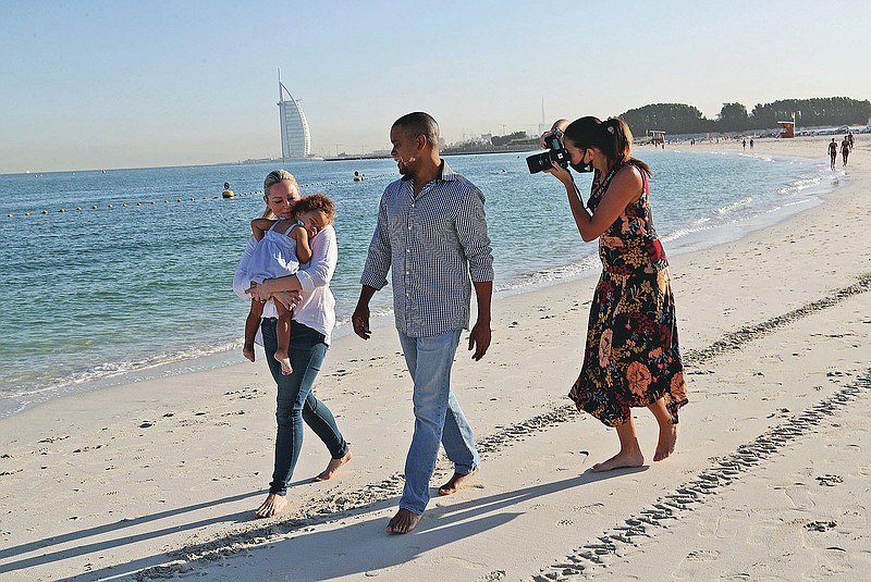 Freelance lifestyle photographer, Paula Hainey takes photos of Darrin Chapman, a pilot recently laid off by long-haul carrier Emirates, and his wife, Jodi Chapman, who carries their daughter Harper, in Dubai, United Arab Emirates, Wednesday, Oct. 14, 2020. Hainey is providing free photoshoots to laid-off expats forced to leave the skyscraper-studded Persian Gulf city because of the coronavirus pandemic. (AP Photo/Kamran Jebreili)