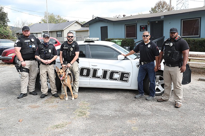 From left, Mountain Pine Police Department Sgt. Ruey Hendrix, Capt. Richard Lobbs, Lt. Travis Bratton, Chief Miguel Hernandez and Cpl. Christopher Haynes gather Friday in front of the police department with Athena, one of the department’s police dogs, for a photograph. - Photo by Richard Rasmussen of The Sentinel-Record