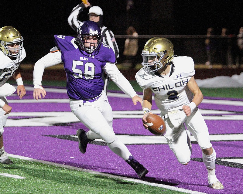 Shiloh Christian Saints Sophomore Eli Wisdom (2) scrambles away from Elkins Elks player Cole Blankenship (58) Friday, October 23, 2020, at Elkins High School, Elkins, Arkansas (Special to NWA Democrat-Gazette/Brent Soule)