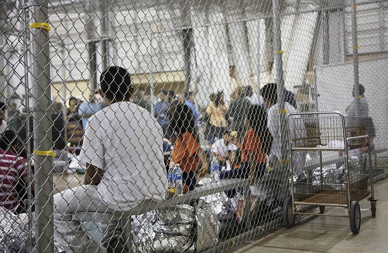 FILE - In this June 17, 2018, file photo provided by U.S. Customs and Border Protection, people who've been taken into custody related to cases of illegal entry into the United States, sit in one of the cages at a facility in McAllen, Texas. A federal judge on Thursday, Oct. 22, 2020, urged the Trump administration to do more to help court-appointed researchers find hundreds of parents who were separated from their children after they crossed the U.S.-Mexico border beginning in 2017. (U.S. Customs and Border Protection's Rio Grande Valley Sector via AP, File)