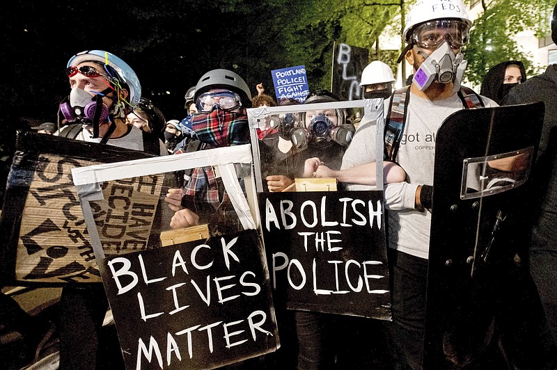 FILE - In this Aug. 2, 2020, file photo, Black Lives Matter protesters march through Portland, Ore. after rallying at the Mark O. Hatfield United States Courthouse. New York, Seattle and Portland, three cities recently labeled "anarchist jurisdictions" by the U.S. Justice Department, are suing to to invalidate the designation and to fight off the Trump administration's efforts to withhold federal dollars. The lawsuit, filed Thursday, Oct. 22, 2020 in U.S. District Court in Seattle, ridiculed Trump's action as offensive to the Constitution and common sense, but said the consequences of withholding federal money during a pandemic "are deadly serious." (AP Photo/Noah Berger, File)