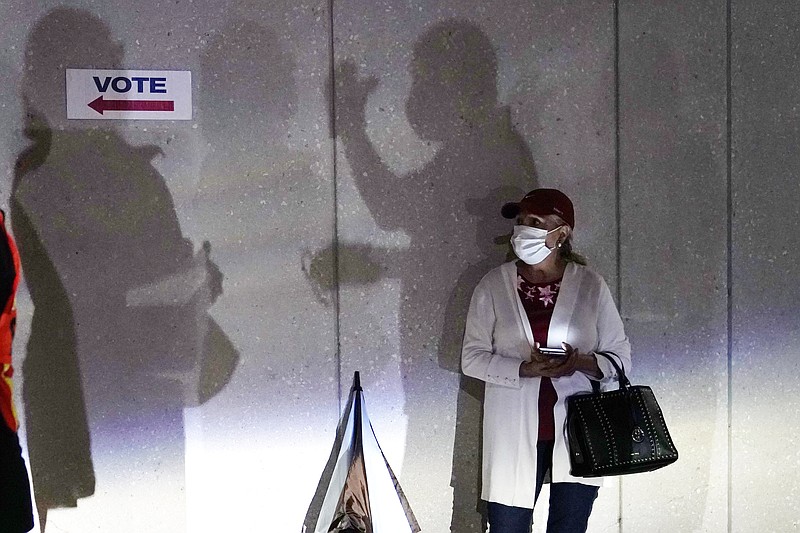 FILE - In this Oct. 19 file photo a woman waits to vote in Miami. Election officials are on high alert amid fears that U.S. polling stations could attract the same strain of partisan violence and civil unrest that erupted on American streets this year. - AP Photo/Lynne Sladky, File