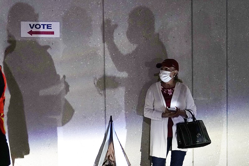 FILE - In this Oct. 19, 2020, file photo a woman waits to vote in Miami. Election officials are on high alert amid fears that U.S. polling stations could attract the same strain of partisan violence and civil unrest that erupted on American streets this year. (AP Photo/Lynne Sladky, File)