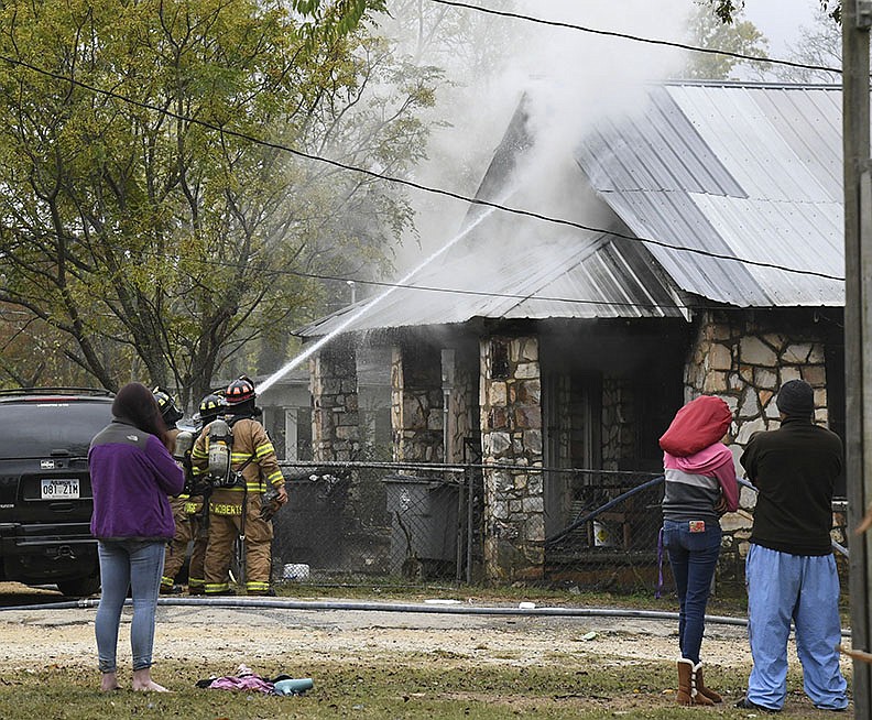 A resident, left, and neighbors look on as the Hot Springs Fire Department works to put out a fire in a duplex located at 608 School St. Sunday afternoon. - Photo By Grace Brown of The Sentinel-Record