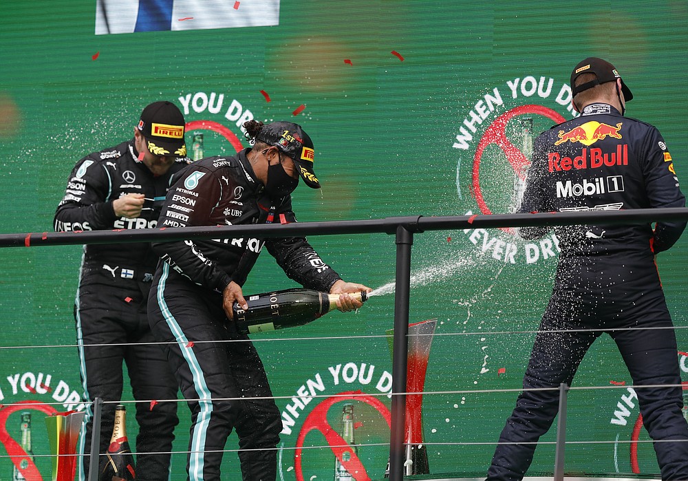 Race winner Mercedes driver Lewis Hamilton of Britain, centre, sprays champagne at the podium with second placed Mercedes driver Valtteri Bottas of Finland, left, and third placed Red Bull driver Max Verstappen of the Netherlandsafter the Formula One Portuguese Grand Prix at the Algarve International Circuit in Portimao, Portugal, Sunday, Oct. 25, 2020. (Rafael Marchante, Pool via AP)