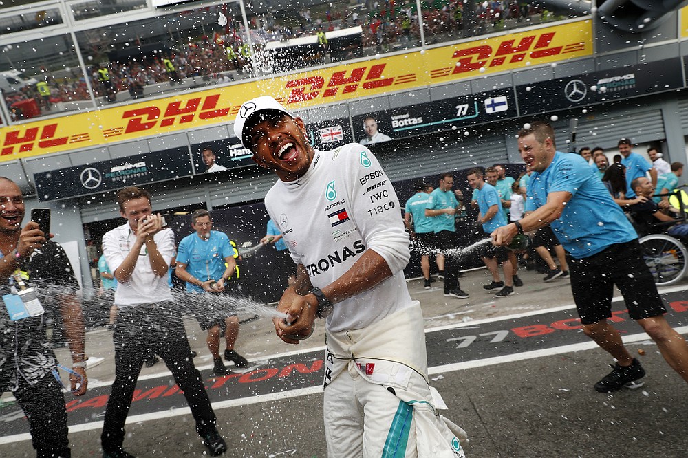 FILE - In this Sunday, Sept. 2, 2018 file photo, Mercedes team members spray champagne at Mercedes driver Lewis Hamilton of Britain celebrating after winning the Formula One Italy Grand Prix at the Monza racetrack, in Monza, Italy. British driver Lewis Hamilton made Formula One history on Sunday, Oct. 25, 2020 winning the Portuguese Grand Prix for a 92nd win to move one ahead of German great Michael Schumacher. (AP Photo/Antonio Calanni, file)