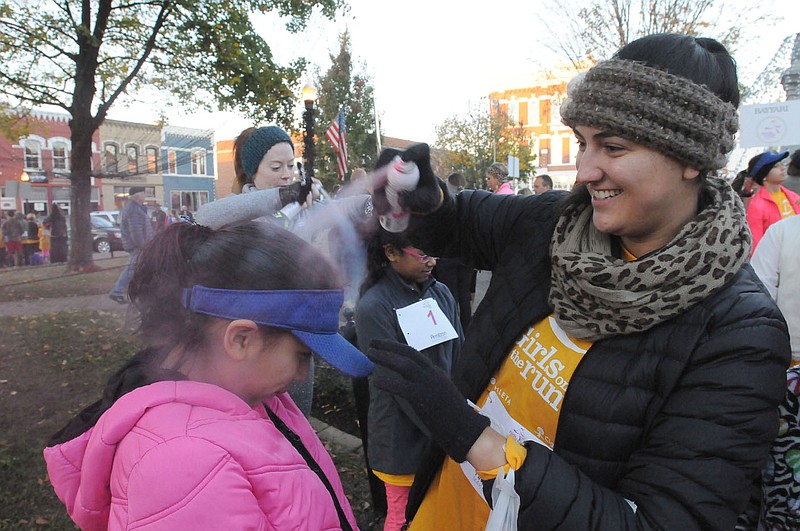 NWA Democrat-Gazette/FLIP PUTTHOFF
READY TO RUN
Kimberly Torres, 8, gets a squirt of colored hair spray coutesy of Jessica Mounce, a teacher at Elmdale Elementary in Springdale, before Kimberly took part Saturday Nov. 12 2016 in the Girls on the Run 5-kilometer run in downtown Bentonville. Hundreds of girls on school teams in Northwest Arkanas took part in pre-run festivities and the 3.1-mile run. Girls on the Run is a national program that encourages pre-teen girls to develop self-respect and a healthy lifestyle through class work and physical activity. The program's finale is a celebratory run. story.lead_photo.caption