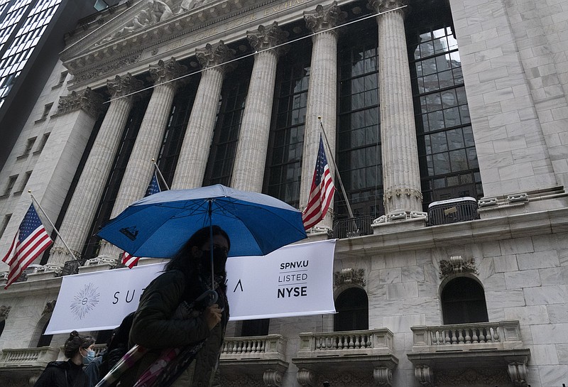 A woman with an umbrella passes the New York Stock Exchange, Monday, Oct. 26, 2020. U.S. stocks are drifting Tuesday, Oct. 27, 2020, as momentum slows a day after Wall Street slumped to its worst loss in a month on worries about rising virus counts and Washington’s inability to deliver more aid to the economy.  The (AP Photo/Mark Lennihan)