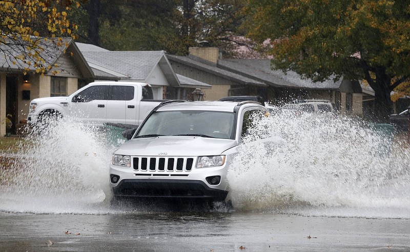 Water rises into the air Thursday, October 29, 2020, as a car passes through a large puddle at the intersection of Emma Avenue and Campbell Drive in Springdale. The National Weather Service forecast for today in Northwest Arkansas is sunny, with a high near 62 degrees and calm winds. Check out nwaonline.com/201030Daily/ and nwadg.com/photos for a photo gallery.(NWA Democrat-Gazette/David Gottschalk)