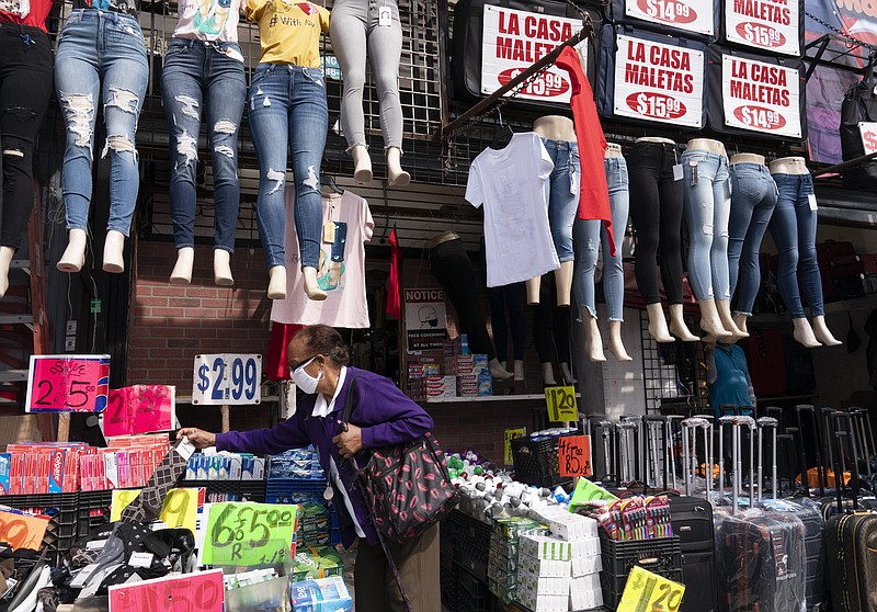 FILE - In this Sept. 25, 2020 file photo, a woman shops at a clothing store in New York. The U.S. economy grew at a sizzling 33.1% annual rate in the July-September quarter — by far the largest quarterly gain on record — rebounding from an epic plunge in the spring, when the eruption of the coronavirus closed businesses and threw tens of millions out of work.  (AP Photo/Mark Lennihan, File)